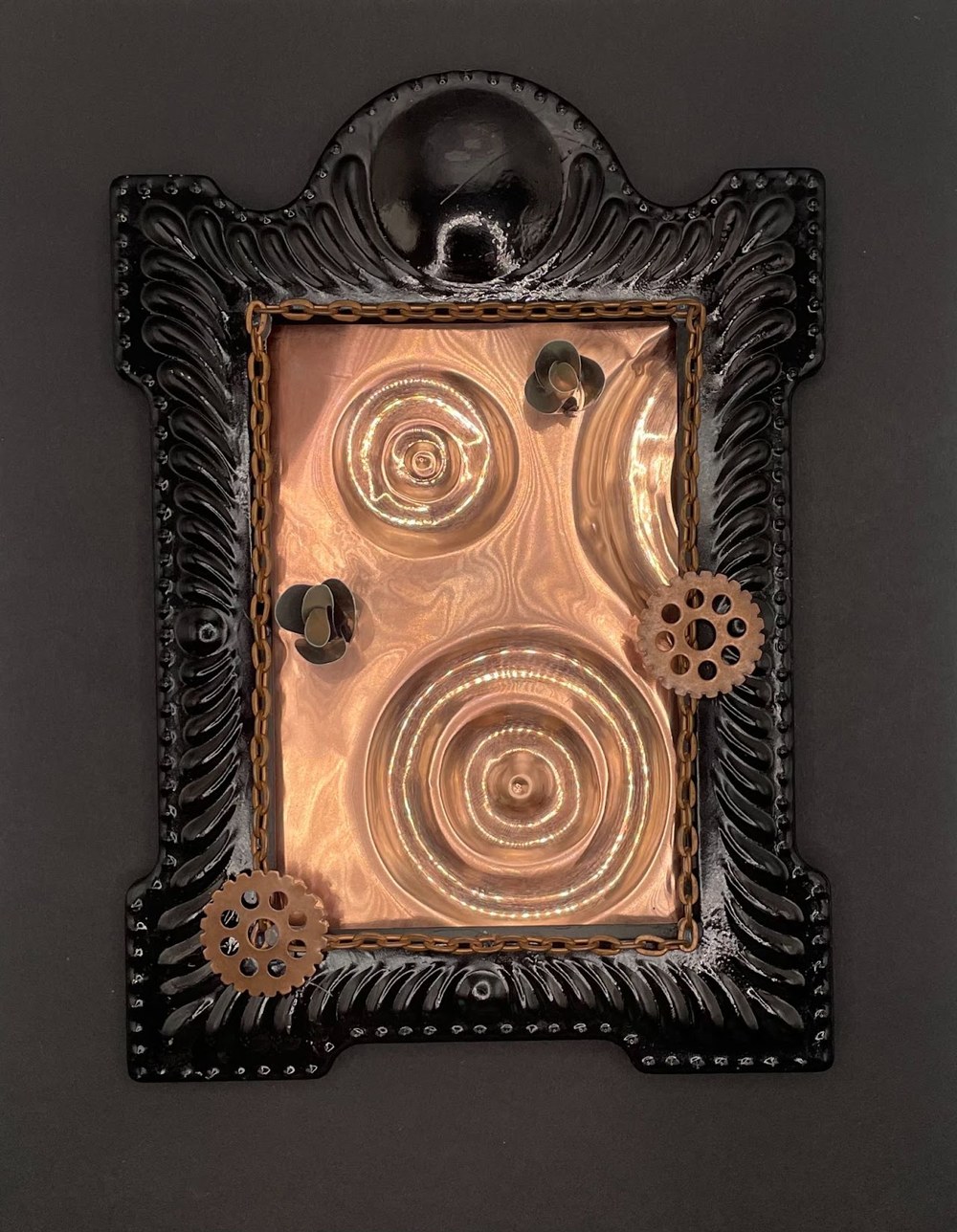 Reclaimed Metal — a black-framed mixed-media piece with rippled copper, gears, and chains