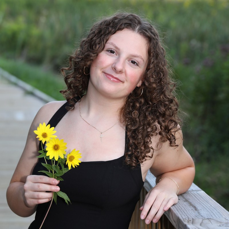 Tess Durham smiling, holding sunflowers