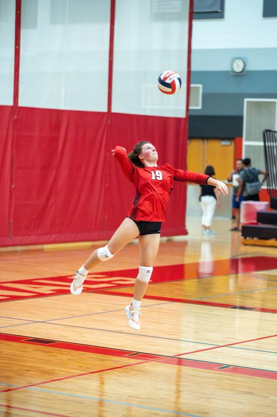 Tess Durham jumping to serve during a varsity volleyball match